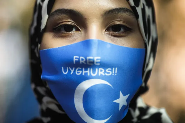 A woman wears a face mask reading “Free Uyghurs” as she attends a protest during the visit of Chinese Foreign Minister Wang Yi in Berlin, Germany, Tuesday, September 1, 2020. German Foreign Minister Heiko Maas meets his Chinese counterpart at the foreign ministry guest house Villa Borsig for bilateral talks. (Photo by Markus Schreiber/AP Photo)