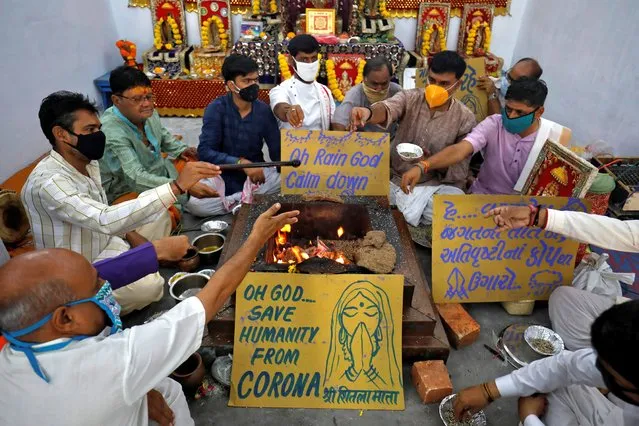 Hindu priests wearing protective face masks perform "havan" (traditional fire ritual) to appease gods to stop rain and to save humanity from the coronavirus disease (COVID-19) inside a temple premises in Ahmedabad, India, August 31, 2020. (Photo by Amit Dave/Reuters)