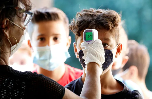 A pupil has his temperature checked as children return to the Simonetta Salacone primary and secondary school for the first time since March, adhering to strict regulations to avoid coronavirus disease (COVID-19) contagion, in Rome, Italy, September 14, 2020. (Photo by Remo Casilli/Reuters)