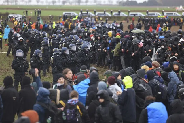 Police officers form a line to block demonstrators on the edge of the opencast lignite mine Garzweiler at the village Luetzerath near Erkelenz, Germany, Saturday, January 14, 2023. (Photo by Oliver Berg/dpa via AP Photo)