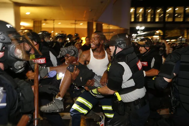 Police and protesters carry a seriously wounded protester into the parking area of the the Omni Hotel during a march to protest the death of Keith Scott September 21, 2016 in Carolina. Scott, who was black, was shot and killed at an apartment complex near UNC Charlotte by police officers, who say they warned Scott to drop a gun he was allegedly holding. (Photo by Brian Blanco/Getty Images)