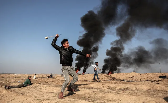 A Palestinian demonstrator swings a slingshot during clashes with Israeli forces near the border with Israel in the southern Gaza strip city of Khan Yunis on February 2, 2018. (Photo by Said Khatib/AFP Photo)