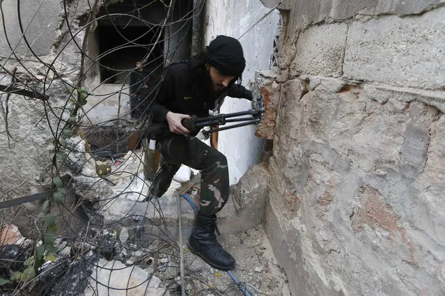 A fighter from the Al-Mujahideen army, which operates under the Free Syrian Army, walks through a hole in the wall on the Zeno street frontline in Aleppo November 18, 2014. (Photo by Hosam Katan/Reuters)