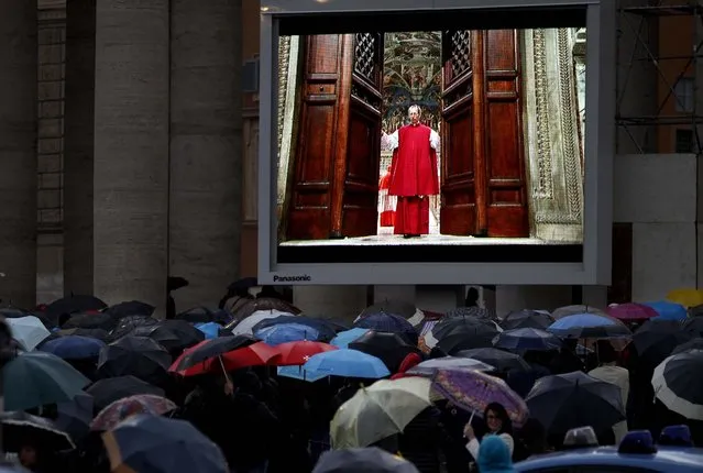 People watch on a video monitor in St. Peter's Square as Monsignor Guido Marini, master of liturgical ceremonies, closes the double doors to the Sistine Chapel in Vatican City at the start of the conclave of cardinals to elect the next pope, on March 12, 2013. Marini closed the doors after shouting “Extra omnes”, Latin for “all out”, telling everyone but those taking part in the conclave to leave the frescoed hall. He then locked it. (Photo by Michael Sohn/Associated Press)