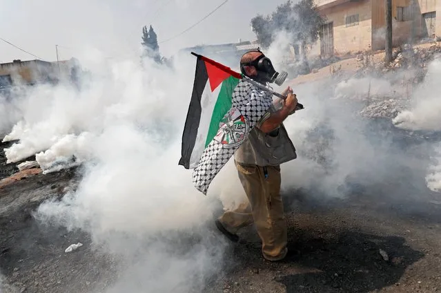A demonstrator holds a Palestinian flag as tear gas is fired by Israeli forces during a protest against normalizing ties with Israel, in Kafr Qaddum town in the Israeli-occupied West Bank on September 11, 2020. (Photo by Mohamad Torokman/Reuters)