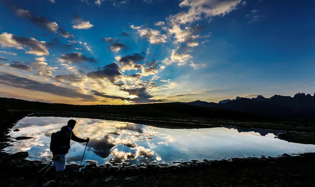 A man walks next to a small lake in the western Austrian village of Grinzens, Austria September 2, 2016. (Photo by Dominic Ebenbichler/Reuters)