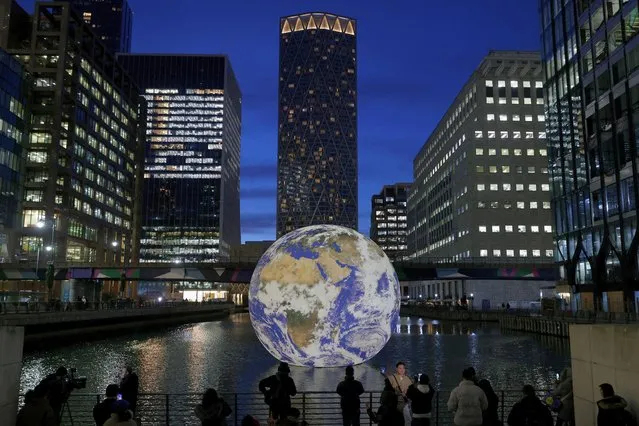 People look at Luke Jerram's “Floating Earth”, an installation as part of the Canary Wharf Winter Lights festival in the financial district in London, Britain on January 17, 2023. (Photo by Kevin Coombs/Reuters)