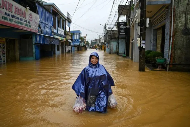 A woman carrying food supplies wades though floodwaters along a street in Central Vietnam's city of Hue on October 17, 2020. (Photo by Manan Vatsyayana/AFP Photo)