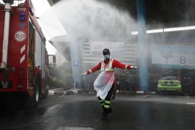 A fire truck sprays water on a worker after a disinfection operation, amid the coronavirus disease (COVID-19) outbreak in Putrajaya, Malaysia on October 15, 2020. (Photo by Lim Huey Teng/Reuters)