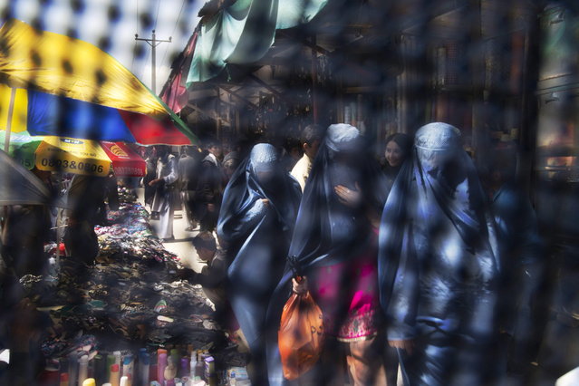 This Thursday, April 11, 2013 photo taken through the eye slit of a burqa, shows Afghan women in Burqa's shopping at a market in Kabul, Afghanistan, Thursday, April 11, 2013. (Photo by Anja Niedringhaus/AP Photo)
