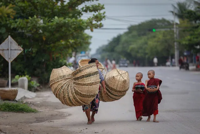 Two novice Buddhist monks walk alongside a basket seller to collect alms following a clerics rule of no footwear nor use of umbrellas in Mandalay, Myanmar, Friday, October 9, 2015. (Photo by Hkun Lat/AP Photo)
