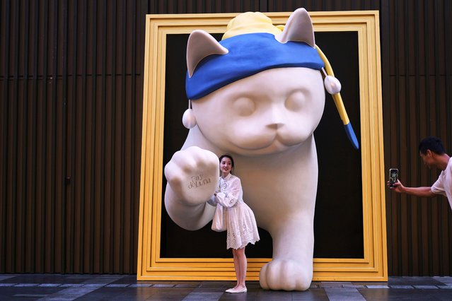 A woman poses for a souvenir photo with a cat statue on display at the Shenzhen Bay commercial district, in Shenzhen, China's Guangdong province, Monday, September 15, 2025. (Photo by Andy Wong/AP Photo)