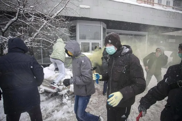 In this photo taken on Friday, March 15, 2013, members of a pro-Kremlin youth group attack pushers of spice, a synthetic drug, one of which is swinging a bat at them in Moscow, Russia. Russian officials and anti-drugs campaigners say that spice has become one of the most dangerous drugs widely available to youngsters and almost impossible to ban because of the constantly changing chemical ingredients. (Photo by Alexander Zemlianichenko Jr/AP Photo)