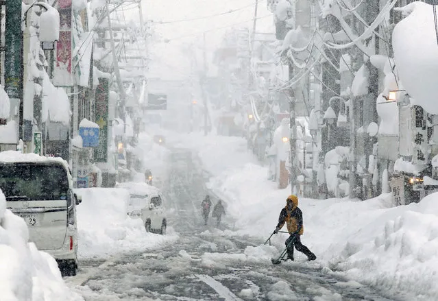 People remove snow on a street in Yuzawa in Niigata Prefecture, northwest of Tokyo, as heavy snow hits a wide area along the Sea of Japan coast on December 17, 2020. (Photo by Kyodo News/Reuters)