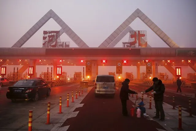 A woman sells hot food to a driver stranded on a highway between Beijing and Hebei province, China, that is closed due to smog on an extremely polluted day November 30, 2015. (Photo by Damir Sagolj/Reuters)