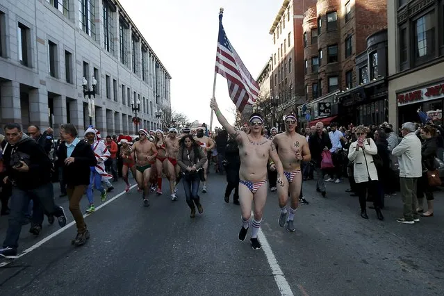 A man carrying a U.S. flag leads the 16th annual Santa Speedo Run through the streets of the Back Bay in Boston, Massachusetts, December 12, 2015. (Photo by Brian Snyder/Reuters)