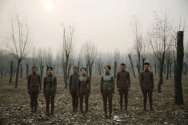 Models pose before they are painted in camouflage colours to blend in with the background for Chinese artist Liu Bolin's artwork “Dongji”, or Winter Solstice, on the second day after China's capital Beijing issued its second ever “red alert” for air pollution, in Beijing, China, December 20, 2015. (Photo by Kim Kyung-Hoon/Reuters)