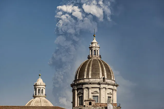 Smoke billows from a crater of Mount Etna volcano, background, as the dome of the Catania Saint Agatha cathedral stands out, in Catania, southern Italy, Thursday, March 4, 2021. Mount Etna, the volcano that towers over eastern Sicily, evokes superlatives. It is Europe's most active volcano and also the continent's largest. And the fiery, noisy show of power it puts on for days or weeks, even years every so often, is always super spectacular. (Photo by Salvatore Allegra/AP Photo)