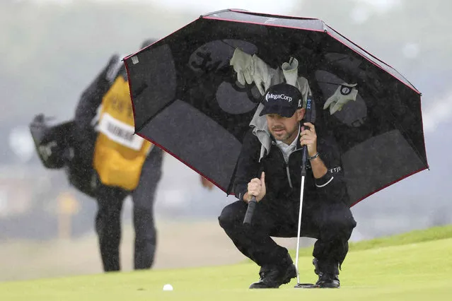 United States' Brian Harman shelters under an umbrella as he looks at his putt on the 11th green during the final day of the British Open Golf Championships at the Royal Liverpool Golf Club in Hoylake, England, Sunday, July 23, 2023. (Photo by Peter Morrison/AP Photo)