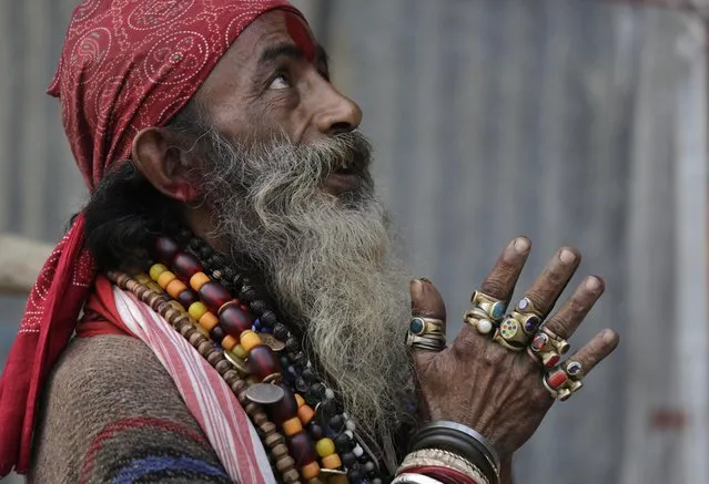 A Hindu holy man on his way to the annual holy dip at Gangasagar, gestures towards a visitor as he rests at a transit camp in Kolkata, India, Wednesday, January 6, 2016. (Photo by Bikas Das/AP Photo)