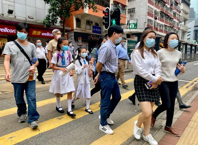 People wearing face masks to help protect against the spread of the coronavirus walk at a street in Hong Kong, Monday, April 26, 2021. (Photo by Vincent Yu/AP Photo)