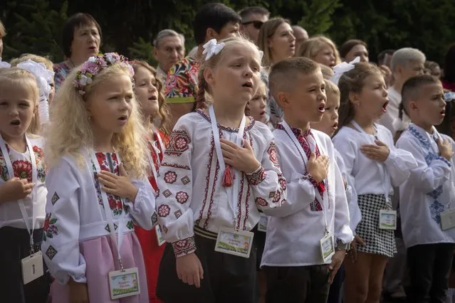 Schoolgirls sing Ukraine's national anthem as they attend a ceremony of the first day in school in Bucha, Ukraine, Friday, September 1, 2023. Ukraine marks Sept. 1 as Knowledge Day, as a traditional launch of the academic year. (Photo by Efrem Lukatsky/AP Photo)