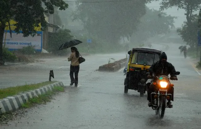 Indian residents make their way home through heavy cyclone rain in Berhampur city, about 180 kilometers south from eastern city Bhubaneswar on October 12, 2013. Nearly half a million people have been evacuated from India's impoverished east coast ahead of a massive cyclone expected to make landfall on October 12 evening, disaster officials said. (Photo by Asit Kumar/AFP Photo)