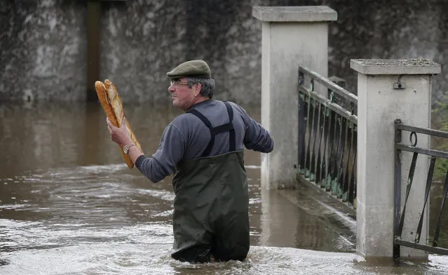 A resident brings French baguettes to his mother's flooded house after heavy rain falls in Chalette-sur-Loing Montargis, near Orleans, France, June 1, 2016. (Photo by Christian Hartmann/Reuters)