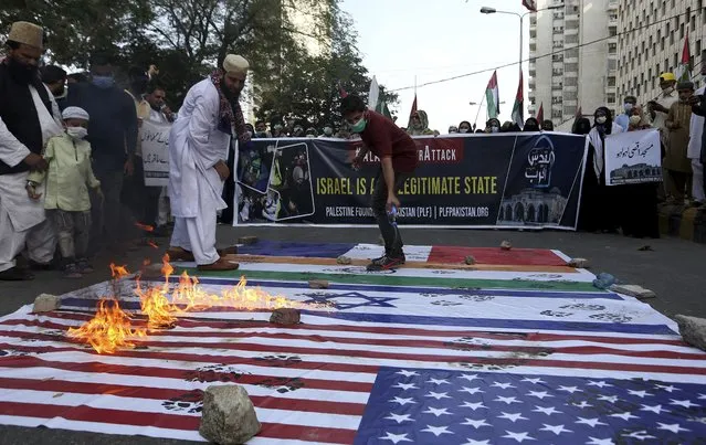 Members of a civil society group burn representations of Israeli, U.S. and Indian flags during a demonstration in support of Palestinians during the latest round of violence in Jerusalem, in Karachi, Pakistan, Tuesday, May 11, 2021. (Photo by Fareed Khan/AP Photo)