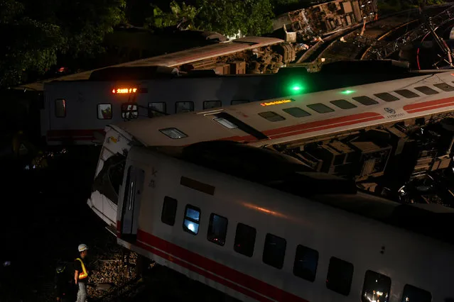Workers walk around derailed train as they prepare to clear the accident site, in Yilan, Taiwan October 22, 2018. At least 22 people have died after an express train derailed and flipped over on a popular coastal tourist route in Taiwan on October 21, the island' s worst rail accident for more than 20 years. Taiwan' s railways administration confirmed 22 people had been killed and said 171 people had been injured, 10 seriously, in the accident in northeastern Yilan county. (Photo by Lee Kun Han/Reuters)