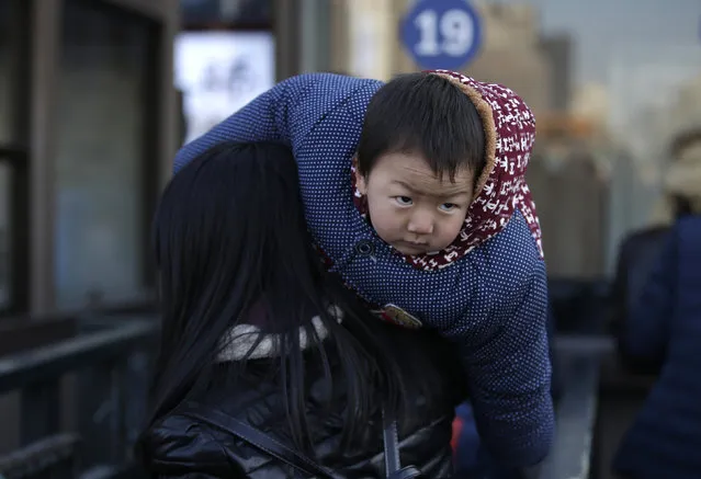 2.5-year-old Wei Yangkun is carried by his mother as they leave Beijing Railway Station for their hometown Xinyang of Henan province, in Beijing, China, January 25, 2016. (Photo by Jason Lee/Reuters)