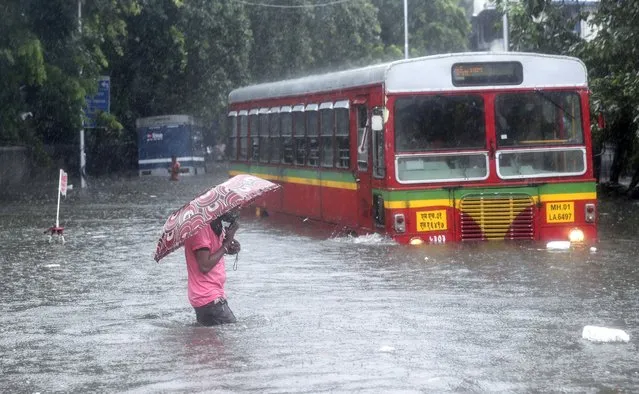 A man makes his way across a flooded street during heavy rains in Mumbai, India, Wednesday, June 9, 2021. (Photo by Rafiq Maqbool/AP Photo)
