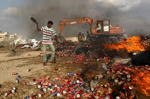 A customs employee throws a liquor bottle into a fire as confiscated contraband is burned and destroyed during a campaign marking International Customs Day in Karachi, Pakistan January 26, 2016. (Photo by Akhtar Soomro/Reuters)