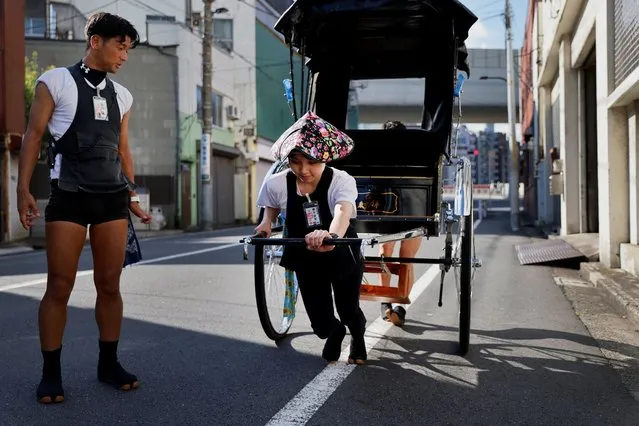 Trainee Yumeka Sakurai, 20, receives rickshaw driving lessons from her colleagues in the Asakusa district, Tokyo, Japan on August 17, 2023. Sakurai joined Tokyo Rickshaw after seeing the pullers actively promote themselves on social media and, after four months of training and overcoming opposition from friends and families, she is now proud to haul passengers in her rickshaw. “I've watched many videos of women training hard and becoming rickshaw drivers themselves. They gave me the confidence that I could do it too if I tried hard”, she said. (Photo by Issei Kato/Reuters)