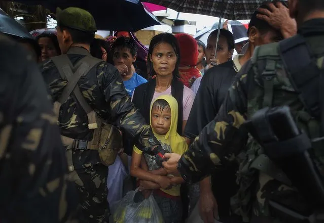 Locals, cordoned off by security forces, seek transportation out at the airport in Tacloban. (Photo by Jes Aznar/The New York Times)