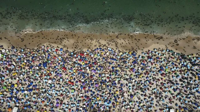 An aerial picture taken with a drone shows sunbathers on a hot day ahead of the spring season at Ipanema beach in Rio de Janeiro, Brazil, 24 September 2023. (Photo by Antonio Lacerda/EPA)