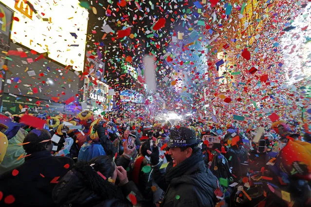 Joey Flores, of California, uses his cellphone as confetti falls during a New Year's celebration in New York's Times Square, Tuesday, January 1, 2019. (Photo by Adam Hunger/AP Photo)