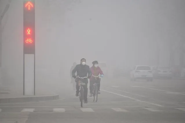 People wearing masks ride bicycles across a street in smog in Liaocheng, Shandong province, China, February 12, 2016. (Photo by Reuters/Stringer)