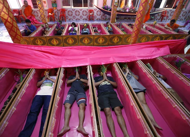 In this Monday, December 31, 2018, file photo, worshippers pray as they take turns sitting in coffins at the Takien temple in suburban Bangkok, Thailand. Worshippers believe that the coffin ceremony – symbolizing death and rebirth – helps them rid themselves of bad luck and are born again for a fresh start in the new year. (Photo by Sakchai Lalit/AP Photo)