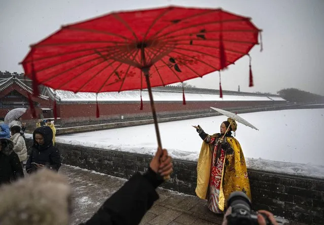 A woman wearing traditional Hanfu clothing has her photo taken outside the  Forbidden City during a snowfall on December 13, 2023 in Beijing, China. Chinas capital Beijing and other parts of northern China saw the seasons first blasts of winter this week with colder than average temperatures and snowfall and closing schools for two days as a precaution. (Photo by Kevin Frayer/Getty Images)