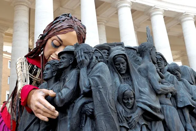 Little Amal, a 3.5 metre tall puppet of a young Syrian refugee girl, embraces the Angels Unawares scuplure in St. Peter's Square as she travels across Europe from Turkey to Britain as part of an 8,000 kilometre walk to raise awareness for the plight of young refugees, Vatican, September 10, 2021. (Photo by Remo Casilli/Reuters)