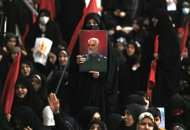 A woman holds up a poster of the late Revolutionary Guard Gen. Qassem Soleimani, who was killed in a U.S. drone attack in 2020 in Iraq, during a commemoration for him at the Imam Khomeini grand mosque in Tehran, Iran, Wednesday, January 3, 2024. Two bombs exploded Wednesday at a commemoration for a prominent Iranian general slain by the U.S. in a 2020 drone strike, Iranian officials said, as the Middle East remains on edge over Israel's war on Hamas in the Gaza Strip. (Photo by Vahid Salemi/AP Photo)