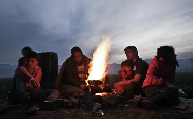 Migrants gather around fire at the northern Greek border station of Idomeni, Tuesday, March 8, 2016. Greek police officials say Macedonian authorities have imposed further restrictions on refugees trying to cross the border, saying only those from cities they consider to be at war can enter as up to 14,000 people are trapped in Idomeni, while another 6,000-7,000 are being housed in refugee camps around the region. (Photo by Visar Kryeziu/AP Photo)