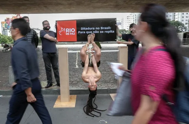 A volunteer demonstrates a method of torture known as “Pau de Arara” in memory of the dead, disappeared, tortured and political prisoners by the Brazilian military dictatorship (1964 – 1985), during an event organized by the NGO Rio de Paz , in front of the Museum of Art of Sao Paulo (MASP), Brazil, 01 April 2019. (Photo by Sebastião Moreira/EPA/EFE)
