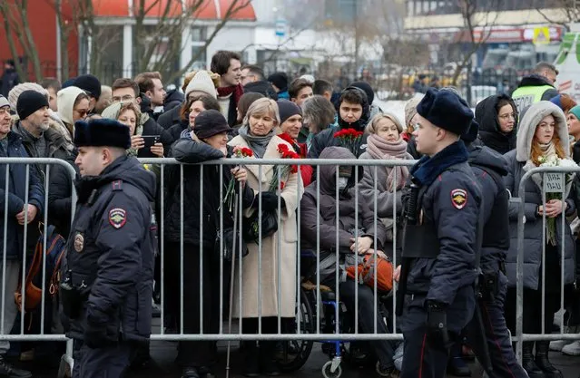 Police officers walk past people, who gather outside the Soothe My Sorrows church and wait for a funeral service and farewell ceremony for Russian opposition politician Alexei Navalny in Moscow, Russia, on March 1, 2024. (Photo by Reuters/Stringer)