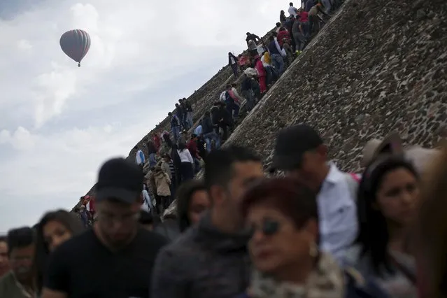 A hot air balloon floats past people standing in line to climb the Pyramid of the Sun and welcome the spring equinox in the pre-hispanic city of Teotihuacan, on the outskirts of Mexico City, Mexico, March 20, 2016. (Photo by Edgard Garrido/Reuters)