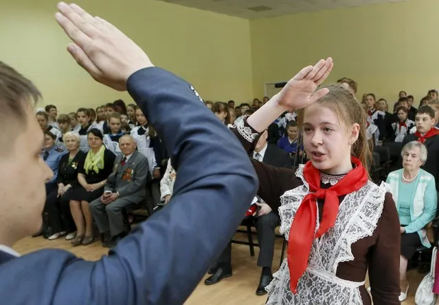 A girl, wearing a red neckerchief, a symbol of the Young Pioneer Organisation, salutes during a ceremony for the inauguration of 45 newly adopted members on the day of its anniversary at school-lyceum number 12 in the Siberian city of Krasnoyarsk, Russia, May 19, 2015. (Photo by Ilya Naymushin/Reuters)