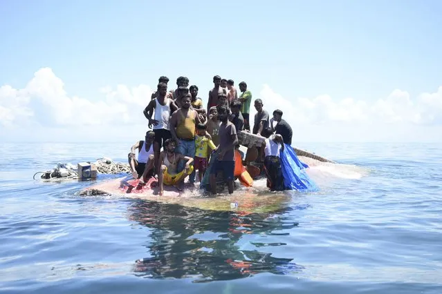 Rohingya refugees stand on their capsized boat before being rescued in the waters off West Aceh, Indonesia, Thursday, March 21, 2024. The wooden boat carrying dozens of Rohingya Muslims capsized off Indonesia's northernmost coast on Wednesday, according to local fishermen. (Photo by Reza Saifullah/AP Photo)