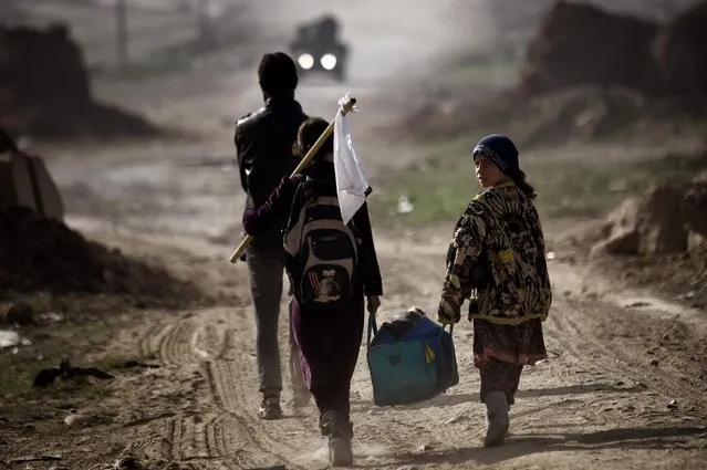 Iraqis carry belongings as they flee Mosul on March 1, 2017, during an offensive by security forces to retake the western parts of the city from Islamic State (IS) group fighters. At least 26,000 people have fled in the 10 days since Iraqi forces launched the push to retake west Mosul, where jihadists put up “fierce” resistance. (Photo by Aris Messinis/AFP Photo)