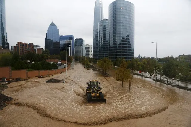 A loader works on a flooded street in Santiago, April 17, 2016. (Photo by Ivan Alvarado/Reuters)